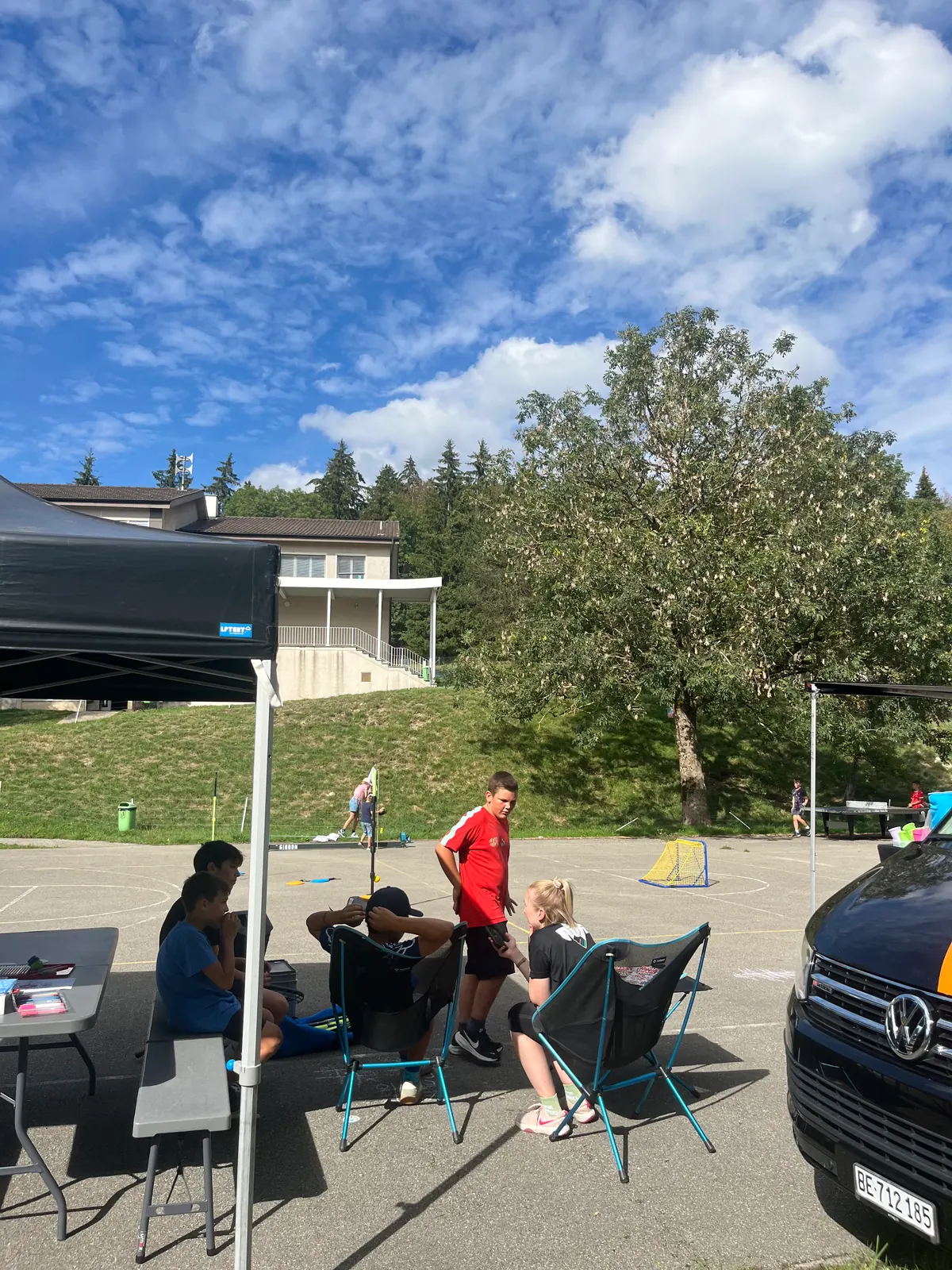 Stand de l'AJR en plein air, avec tente, chaises et jeunes